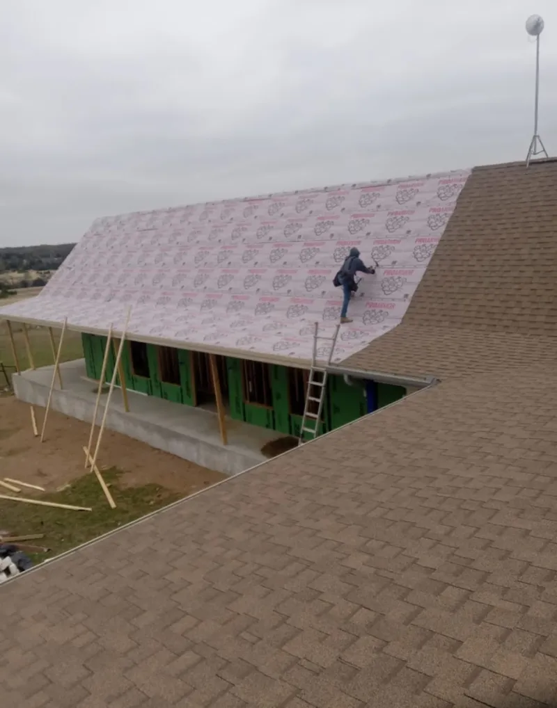 Worker preparing underlayment for a metal roof installation in Kansas City